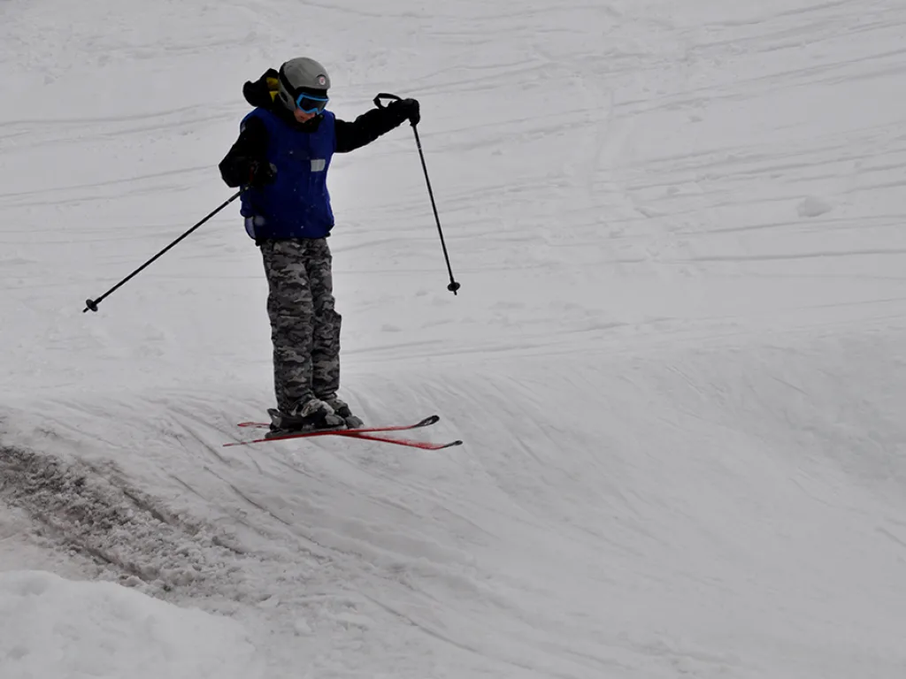 Skifahrer steht mit erhobenen Stöcken auf der Piste.